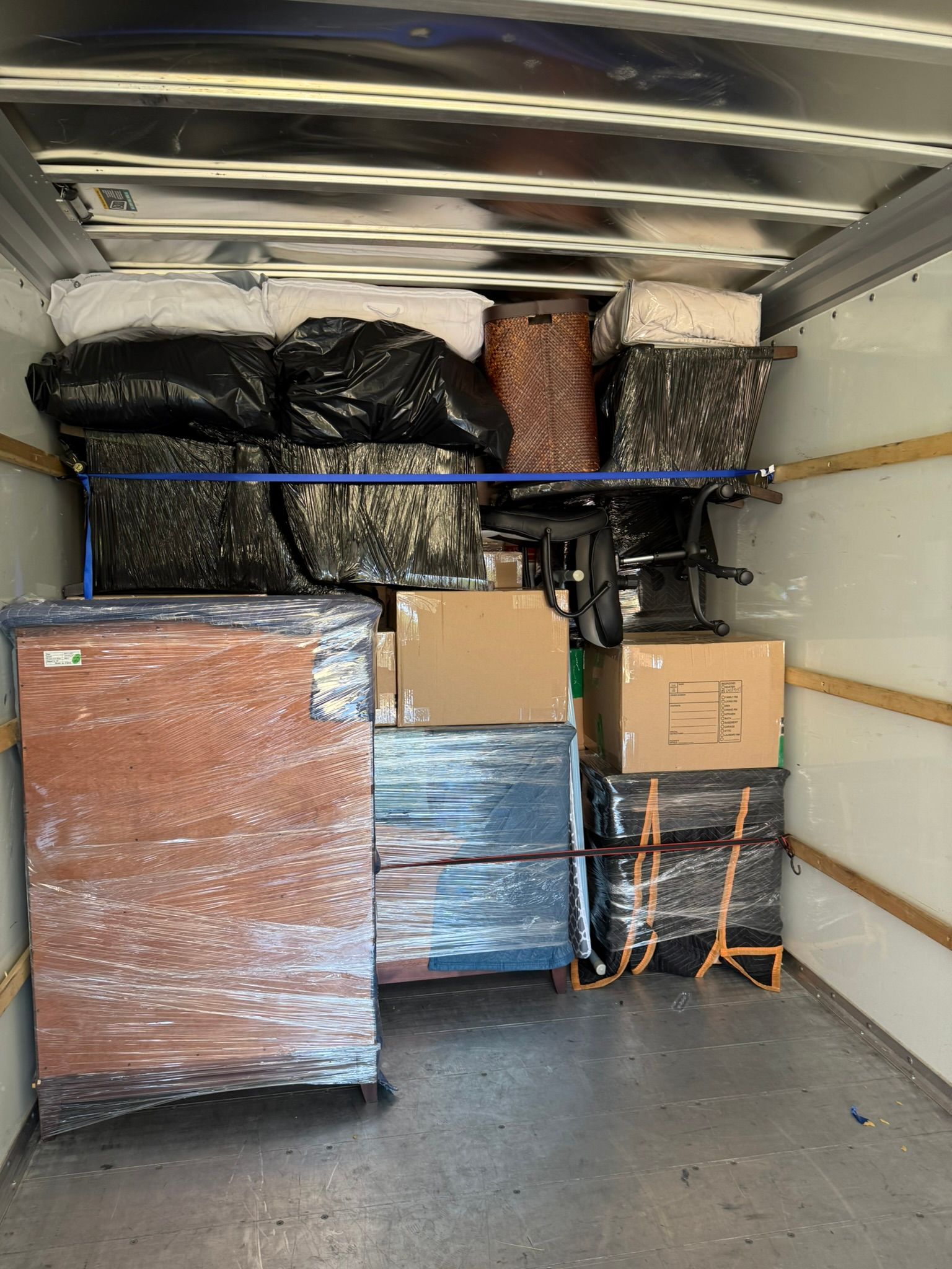 Inside a moving truck: furniture and boxes stacked for transport.
