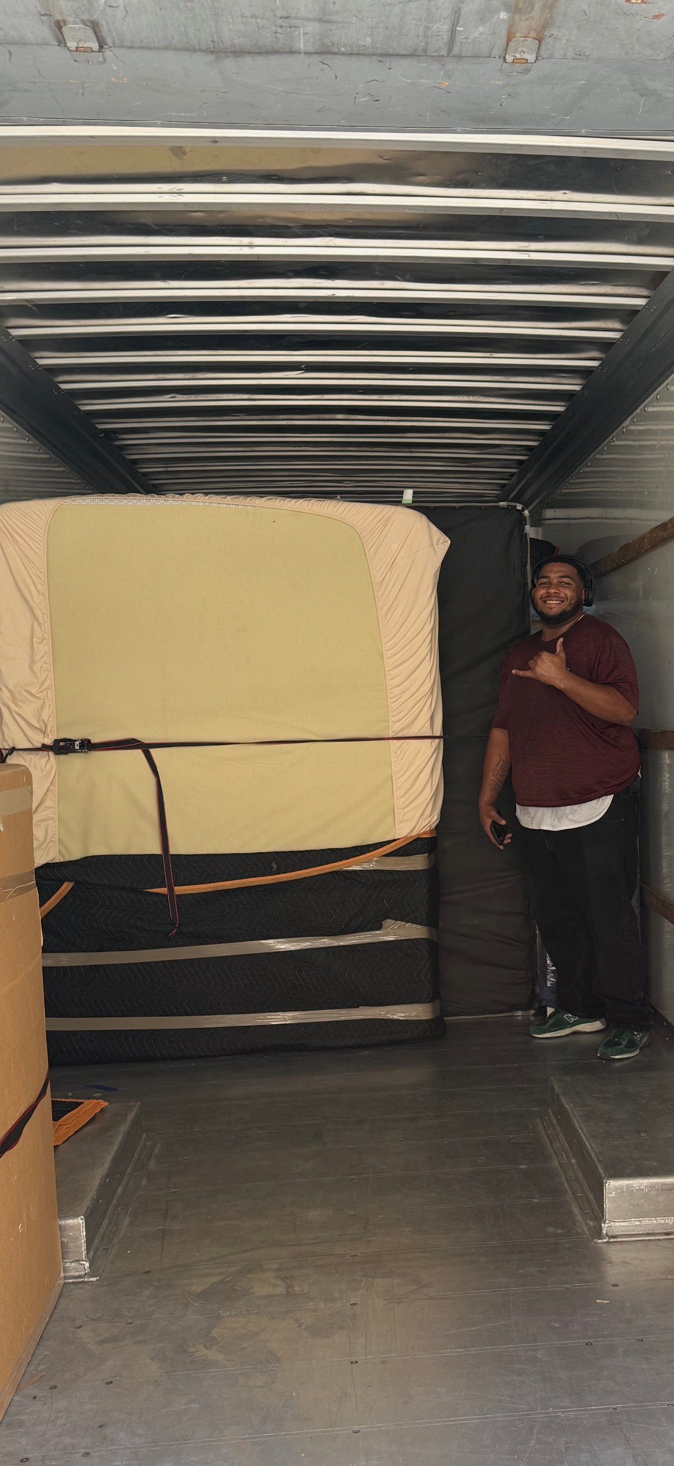 Man in a truck with a mattress and boxes. He gives the shaka sign.