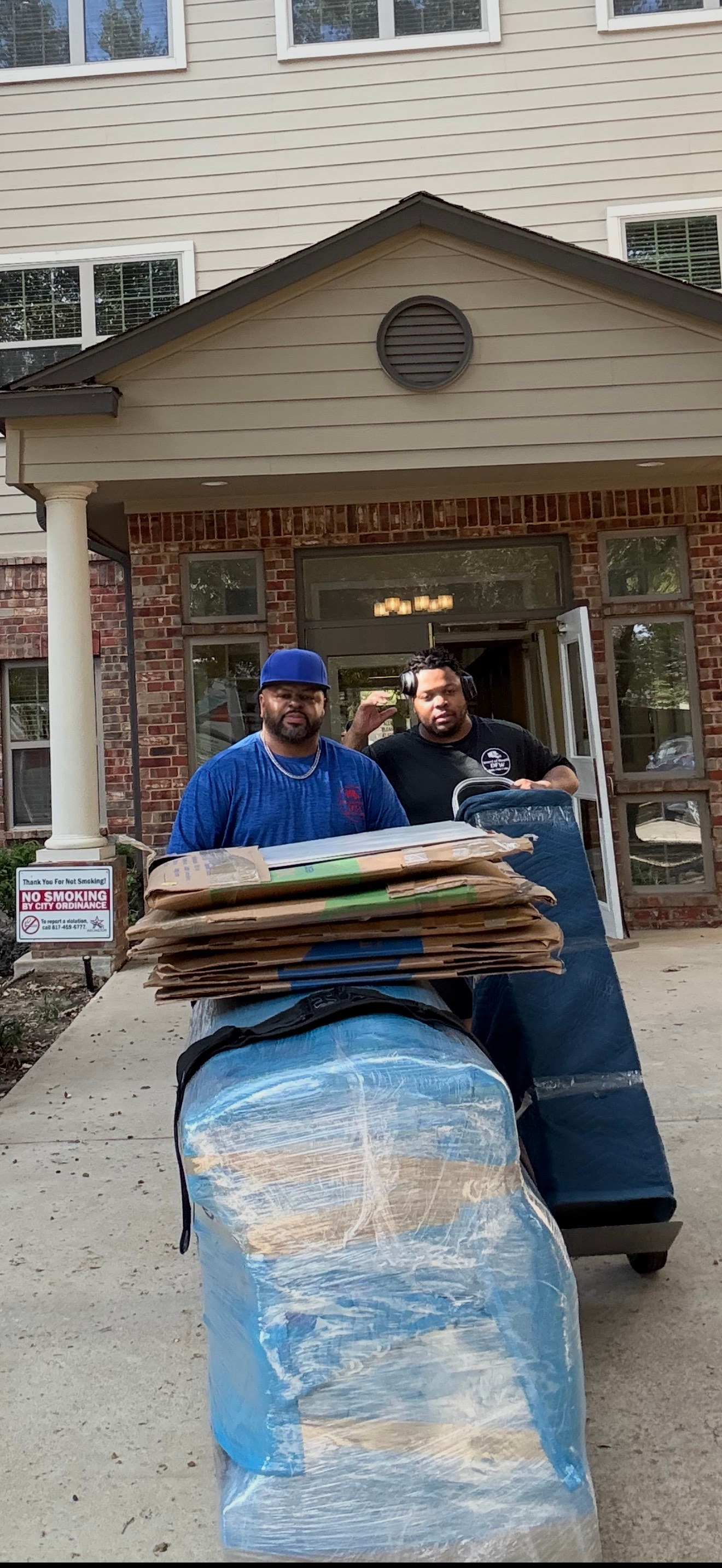 Two people moving furniture out of a building.