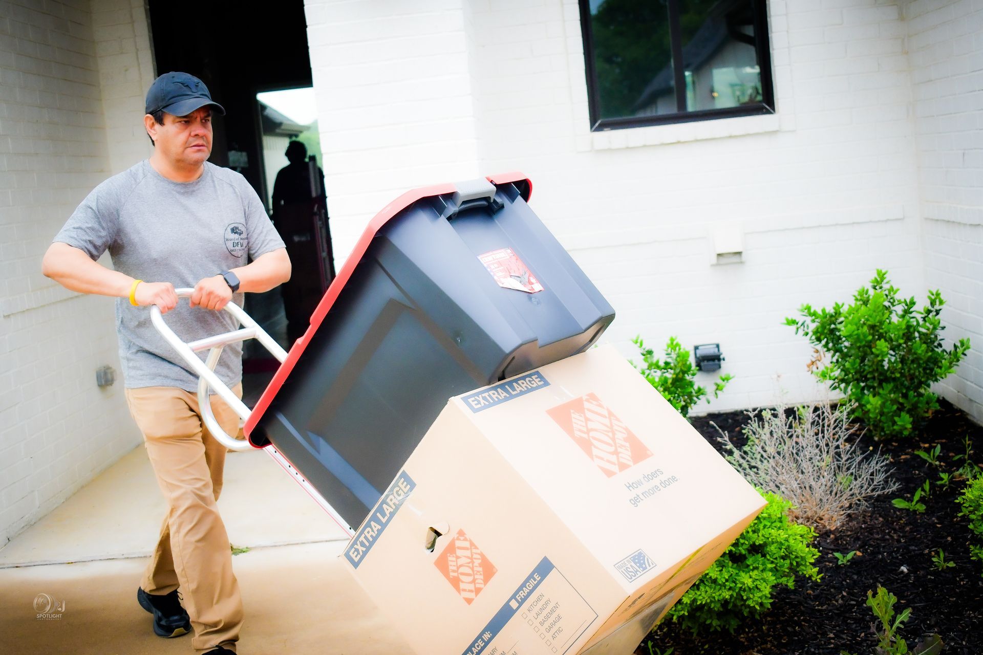 Person pushing a dolly with boxes outside a building