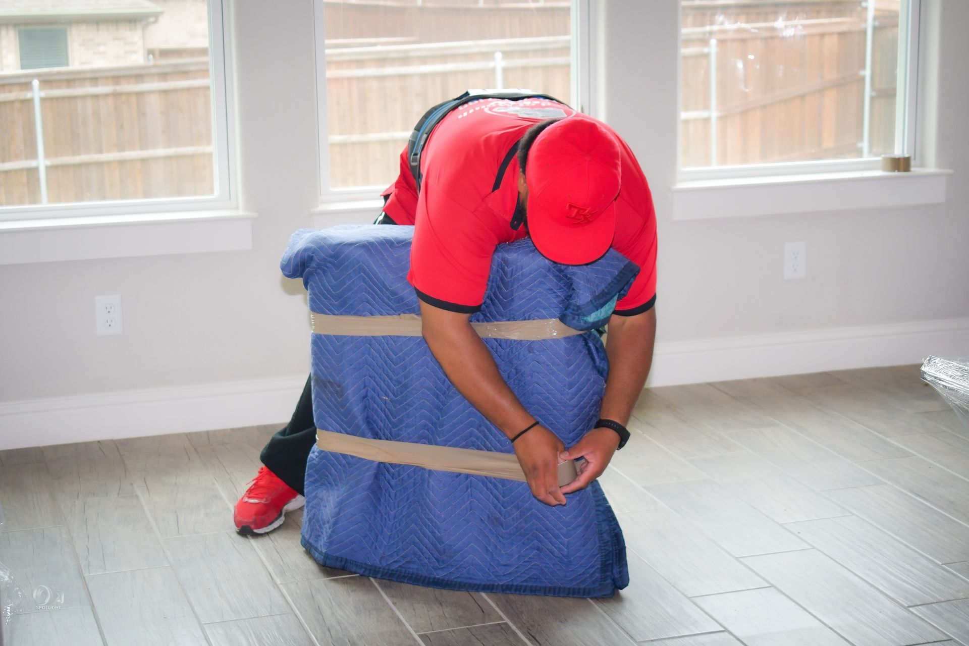 Person in red shirt and cap kneeling by a blue padded object in a bright room
