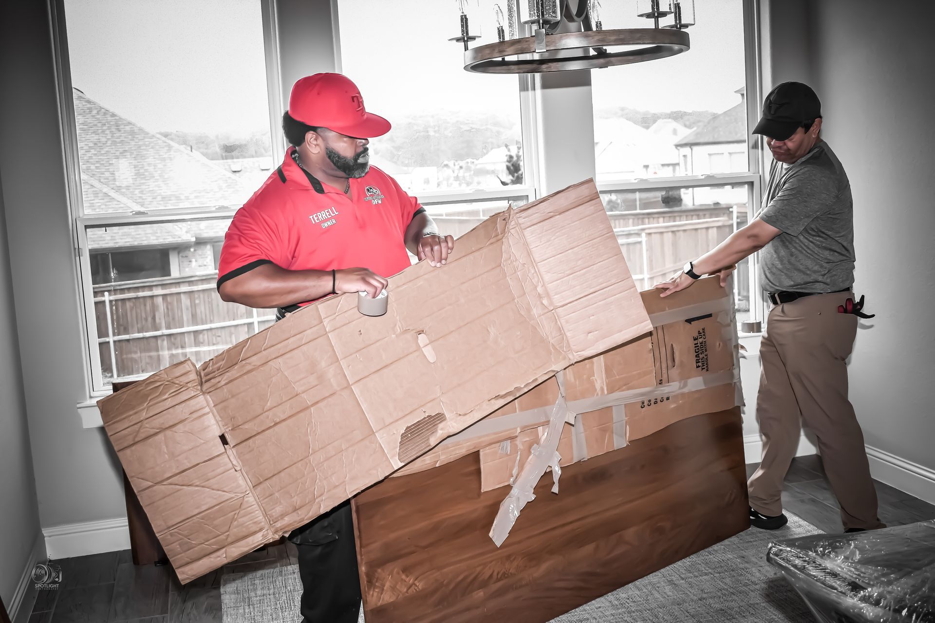 Two movers carrying a large cardboard box into a home interior