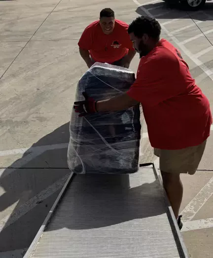 A man in a red shirt is pushing a suitcase on a ramp