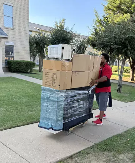 A man is pushing a cart full of boxes down a sidewalk.