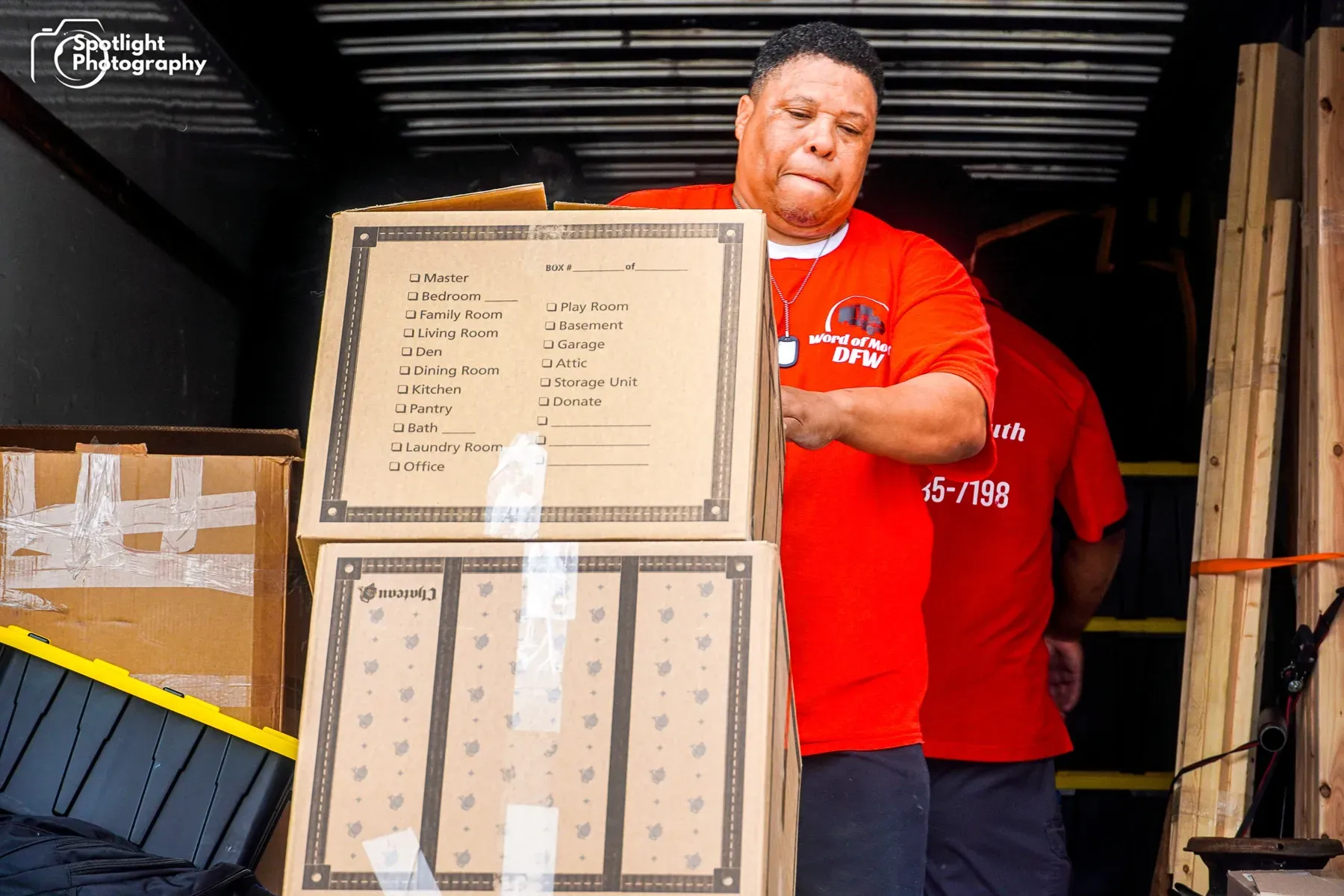 A man in a red shirt is holding a cardboard box.