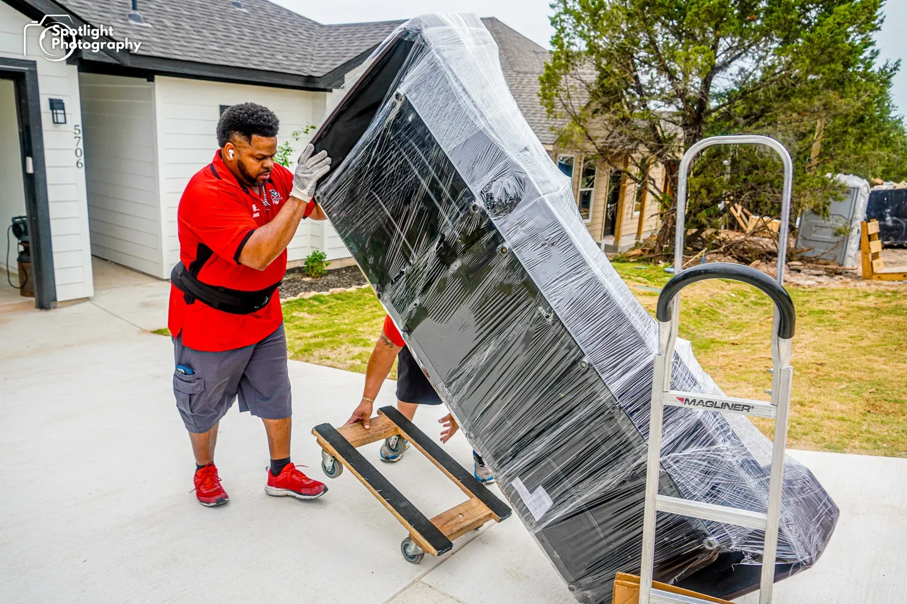 Two men are moving a couch on a dolly.