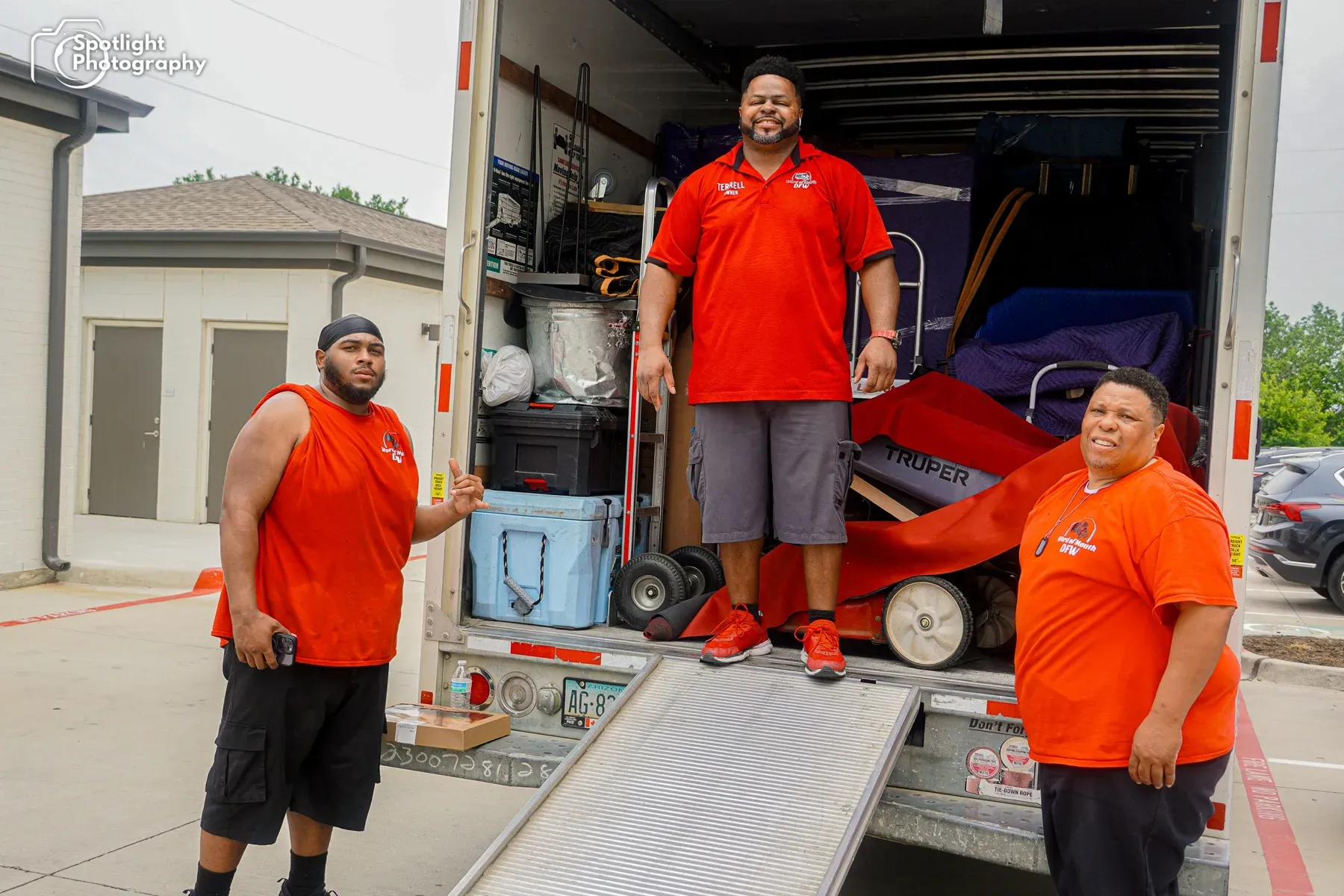 Three men are standing in front of a moving truck.