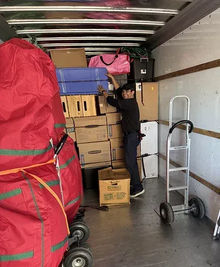 A man is loading boxes into a moving truck.