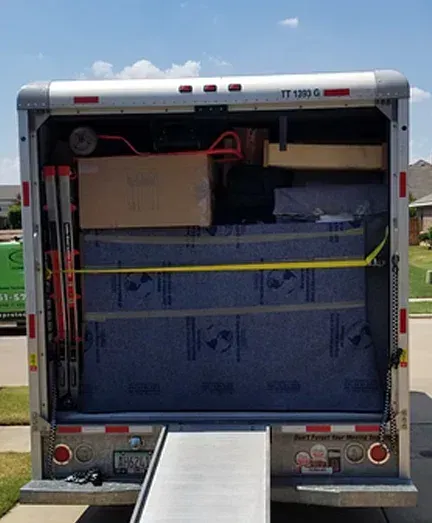 A moving truck is loaded with boxes and a ramp