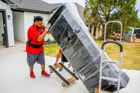 Two men are moving a couch on a dolly.