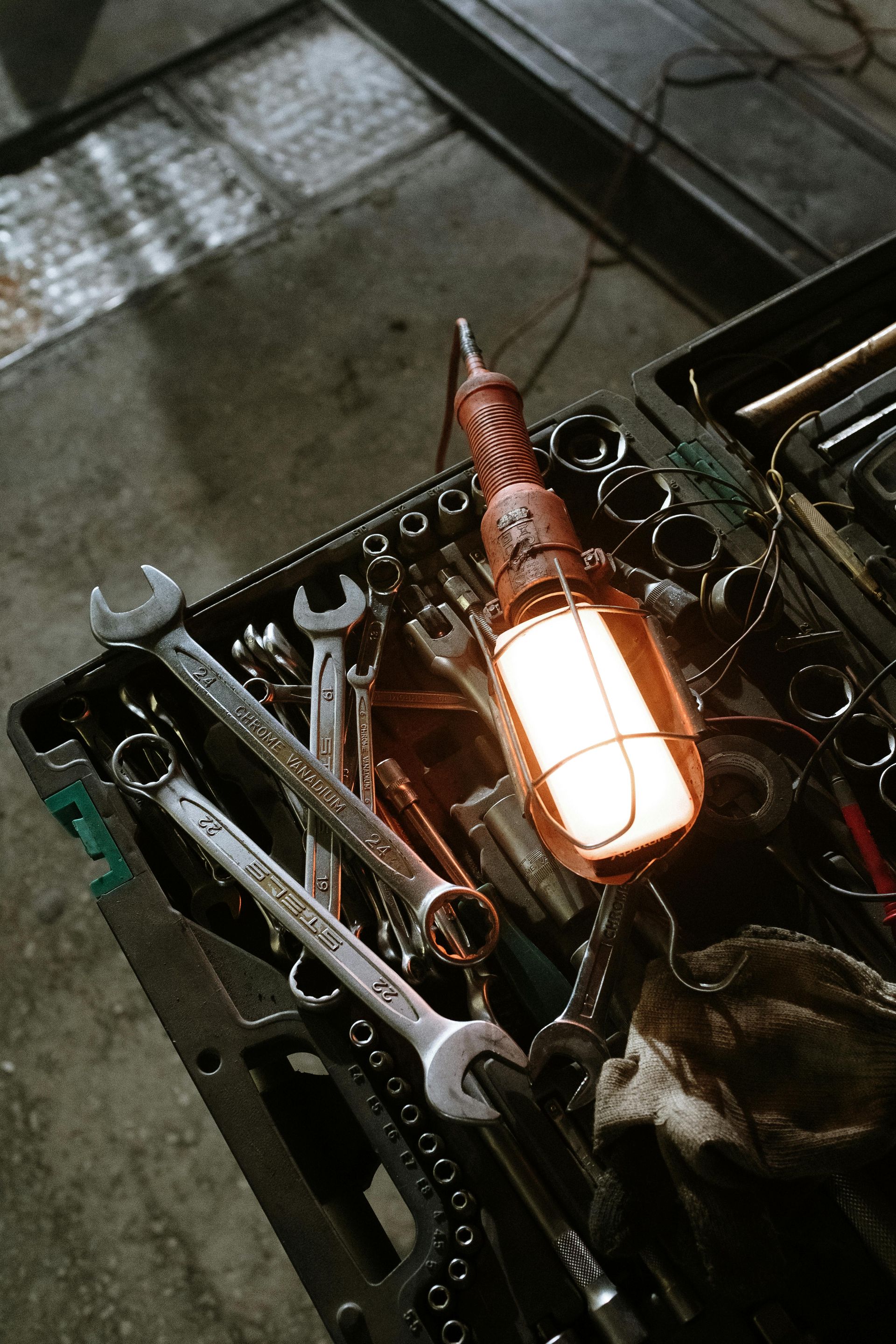 Wrench set in a toolbox with a lit work light, dimly lit garage setting.