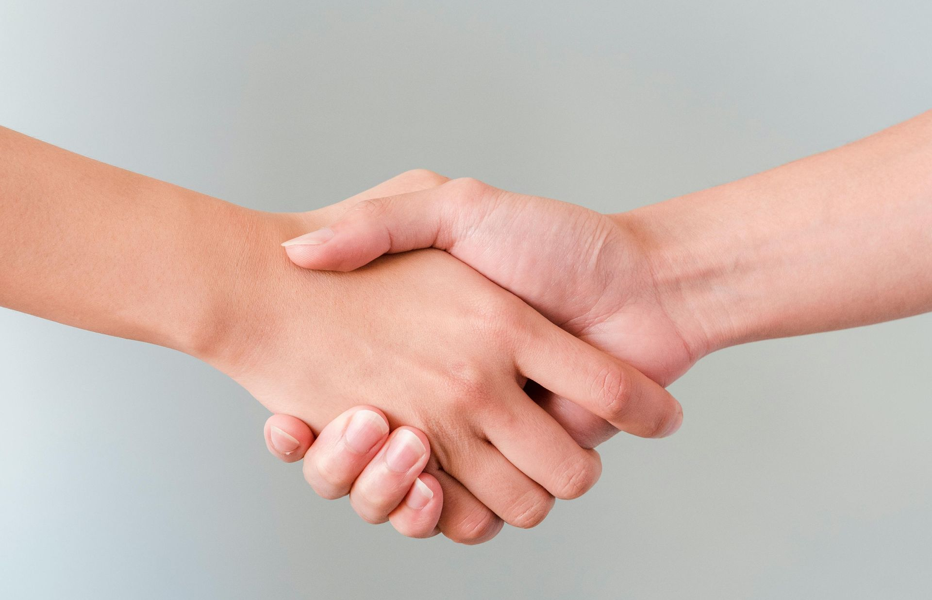 Two hands clasped in a handshake, offering a symbol of agreement or partnership.