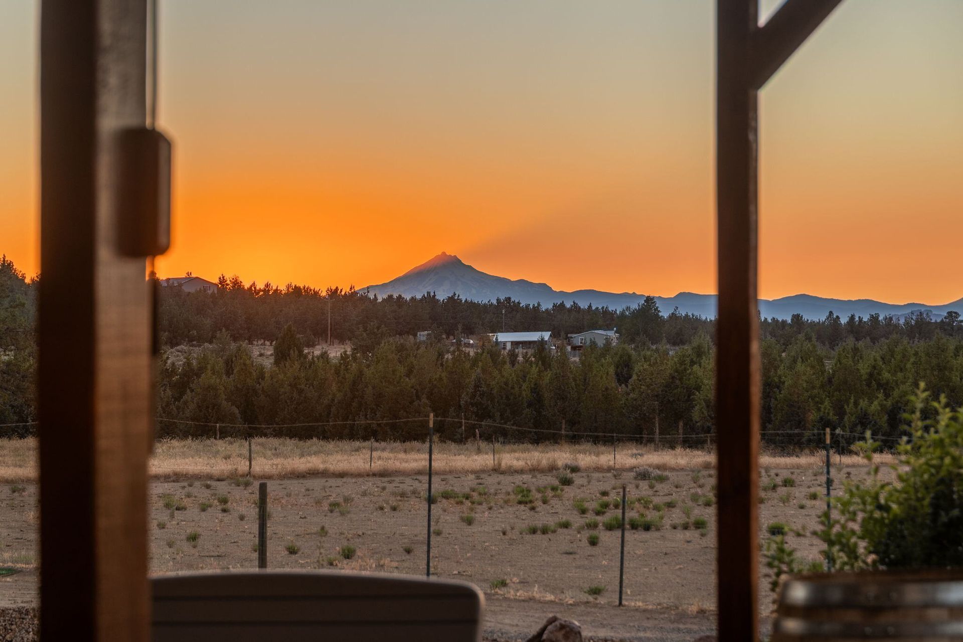 A view of a sunset from a porch with a mountain in the background.