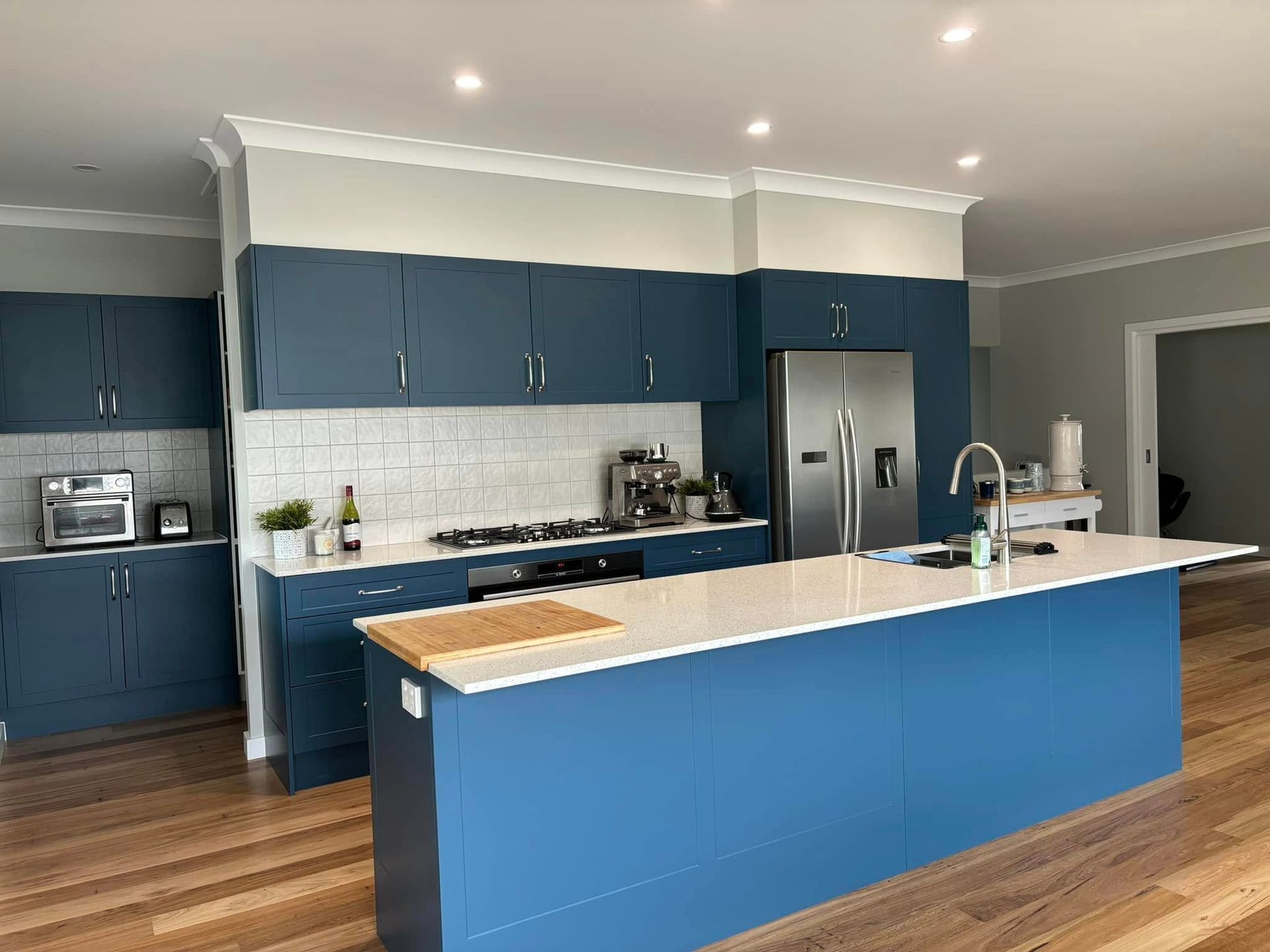 Blue kitchen with white countertops and stainless steel appliances.