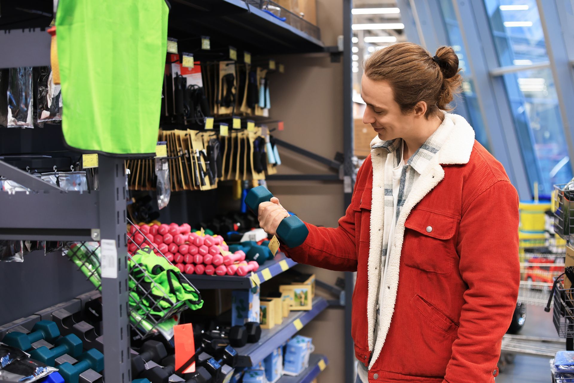 Man holding dumbbell inside gym equipment store browsing free weights and fitness gear.