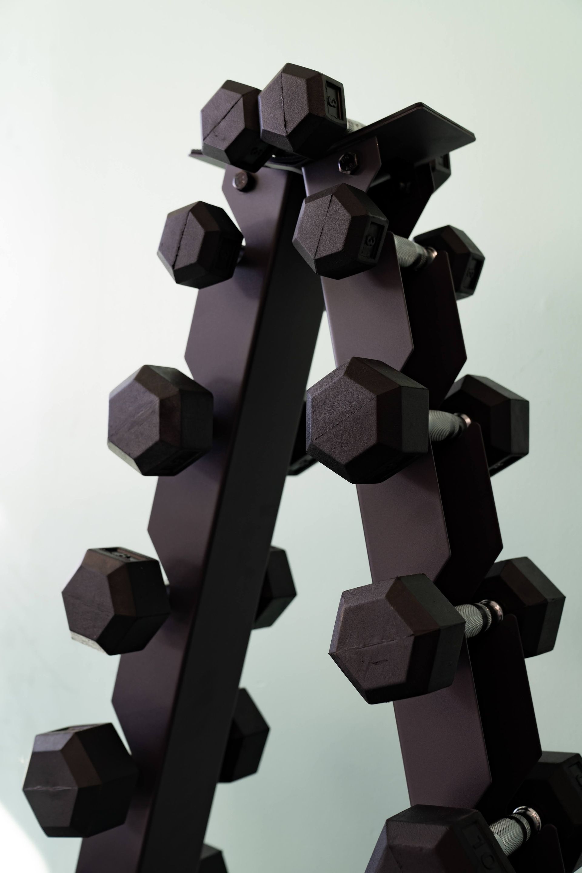 A black, A-frame weight rack holding five pairs of black hexagonal dumbbells.