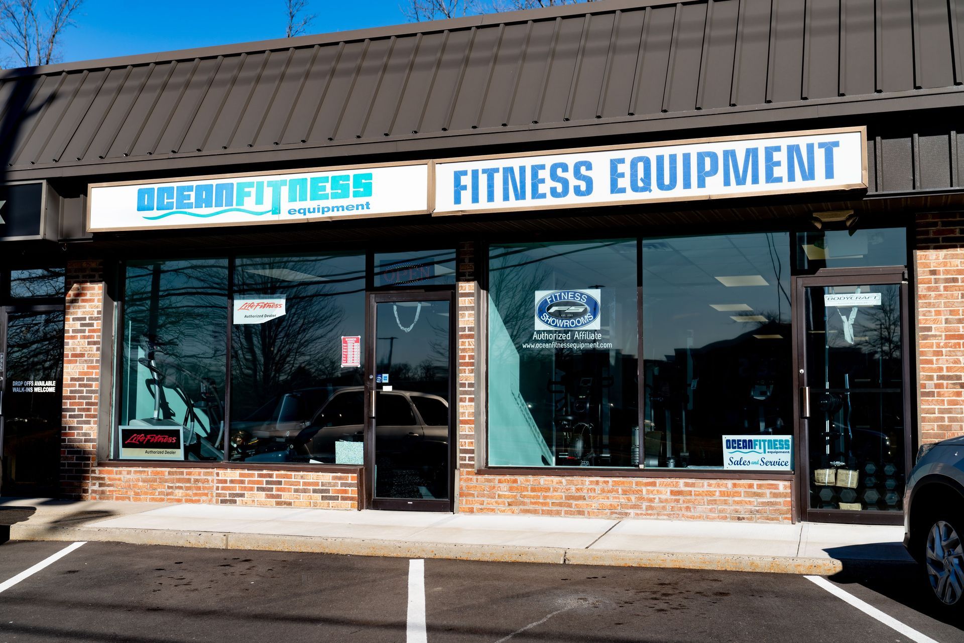 Storefront of DreamFitness, a fitness equipment shop with brick walls and a dark metal awning, under a clear blue sky.