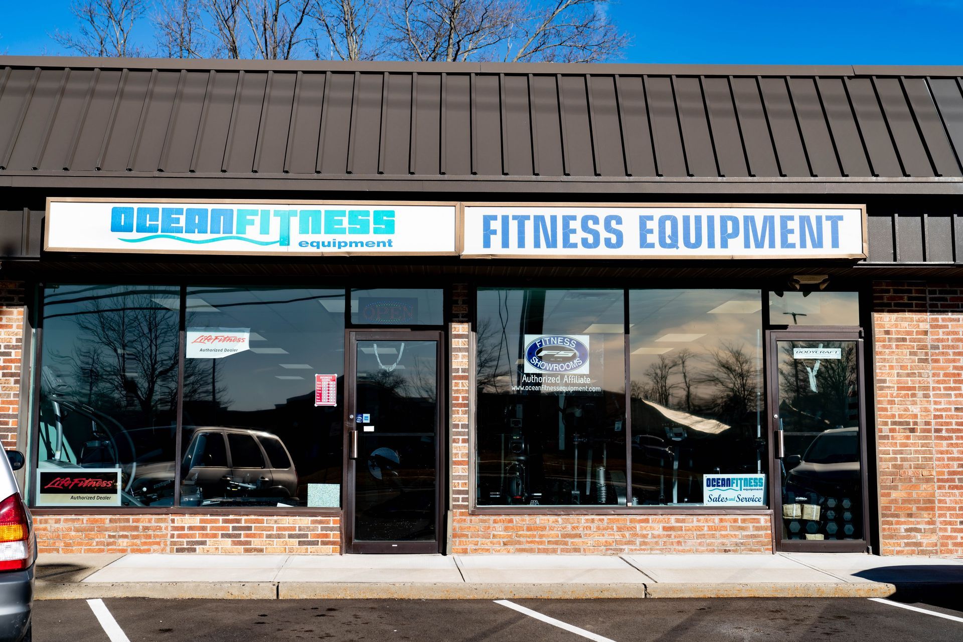 Storefront of Ocean Fitness, a fitness equipment shop with brick facade and large glass windows under a dark metal roof.