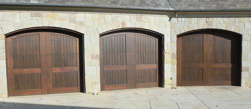 A row of wooden garage doors on a stone building.