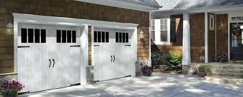 A couple of white garage doors are sitting in front of a house.