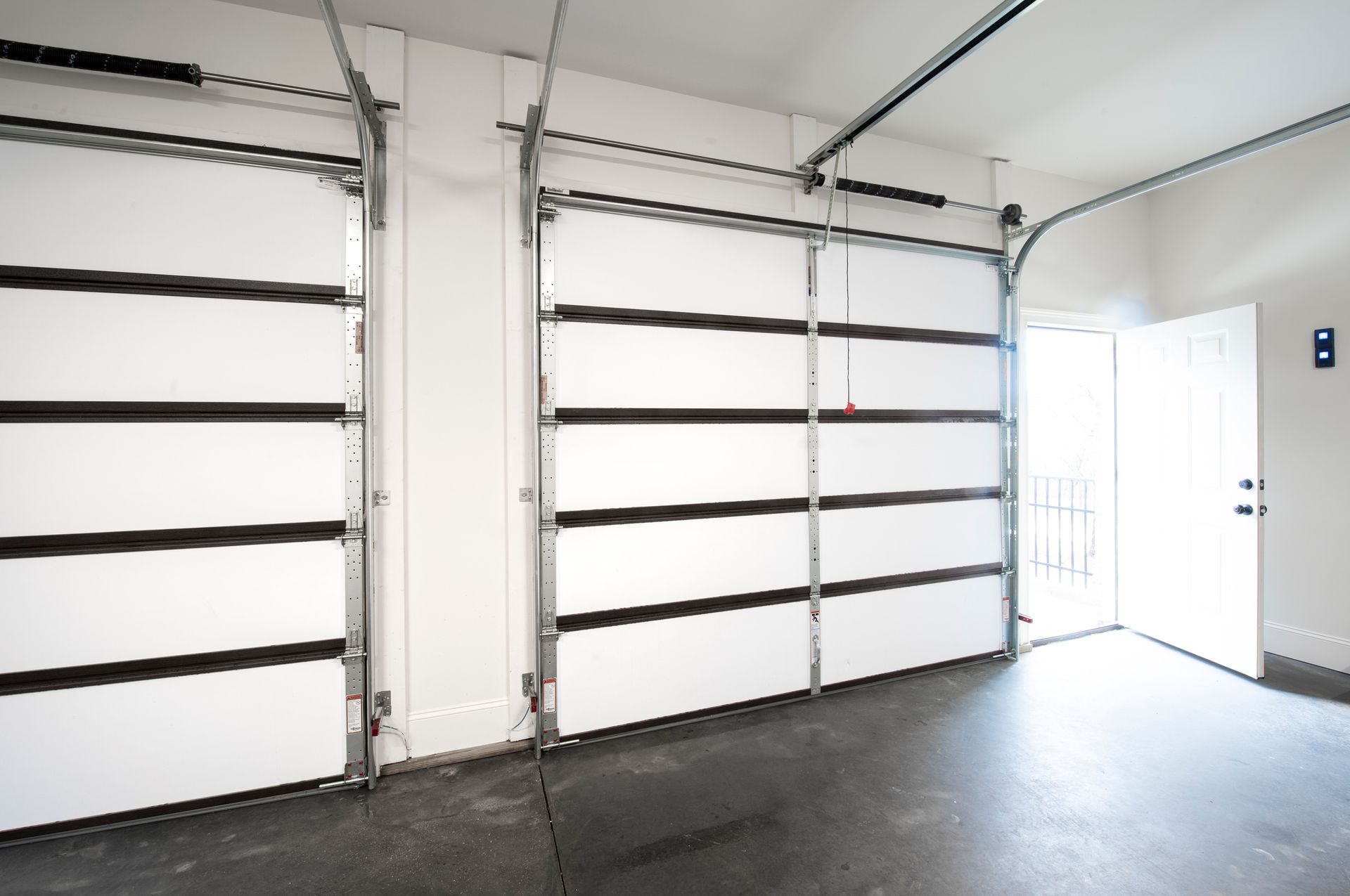 An empty garage with a white door and a black floor