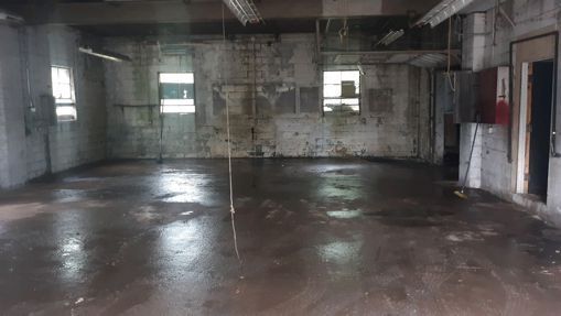 a large empty room with a concrete floor and brick walls .