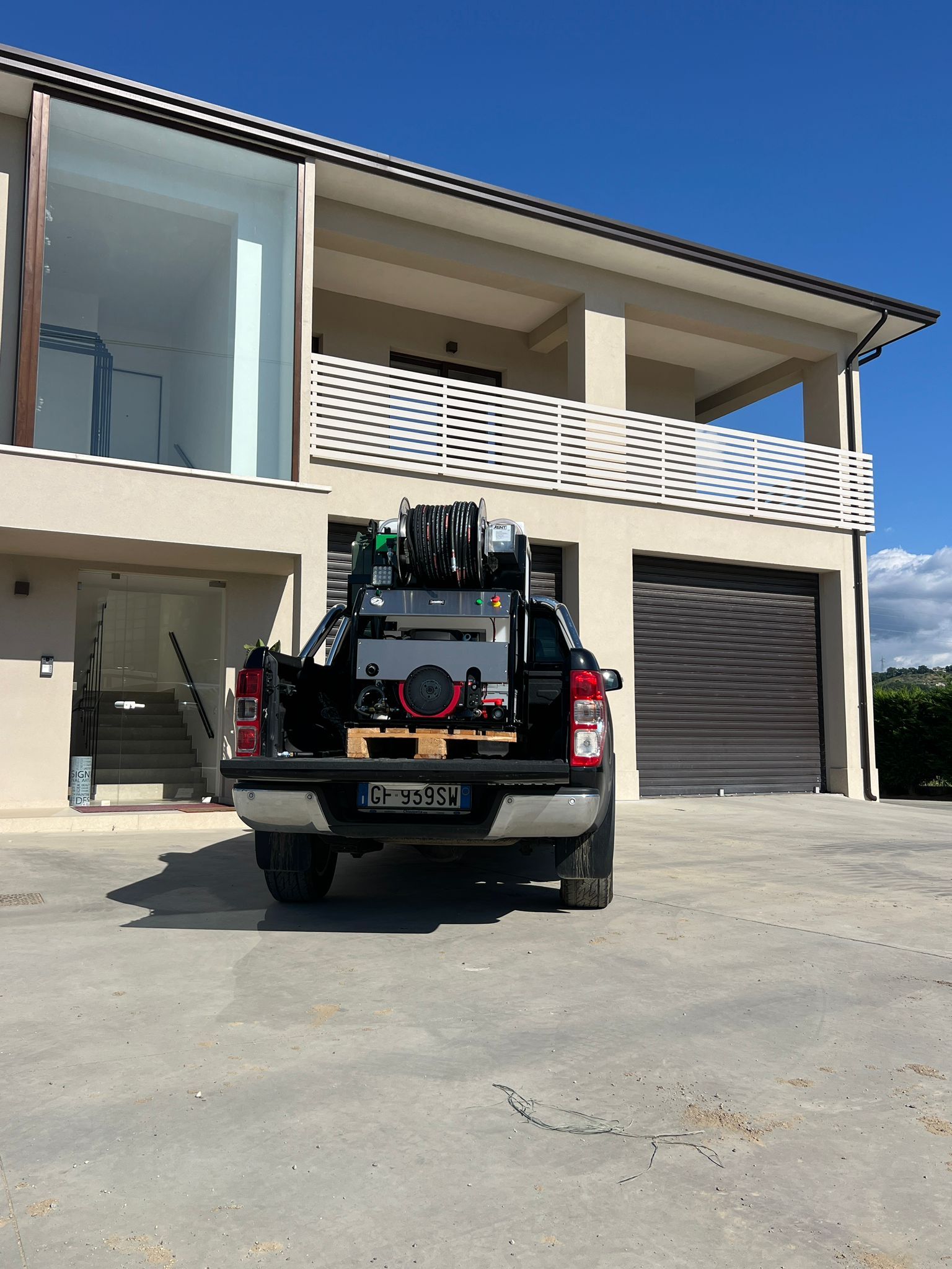 Un pick-up nero è parcheggiato davanti a una casa beige a due piani con garage.