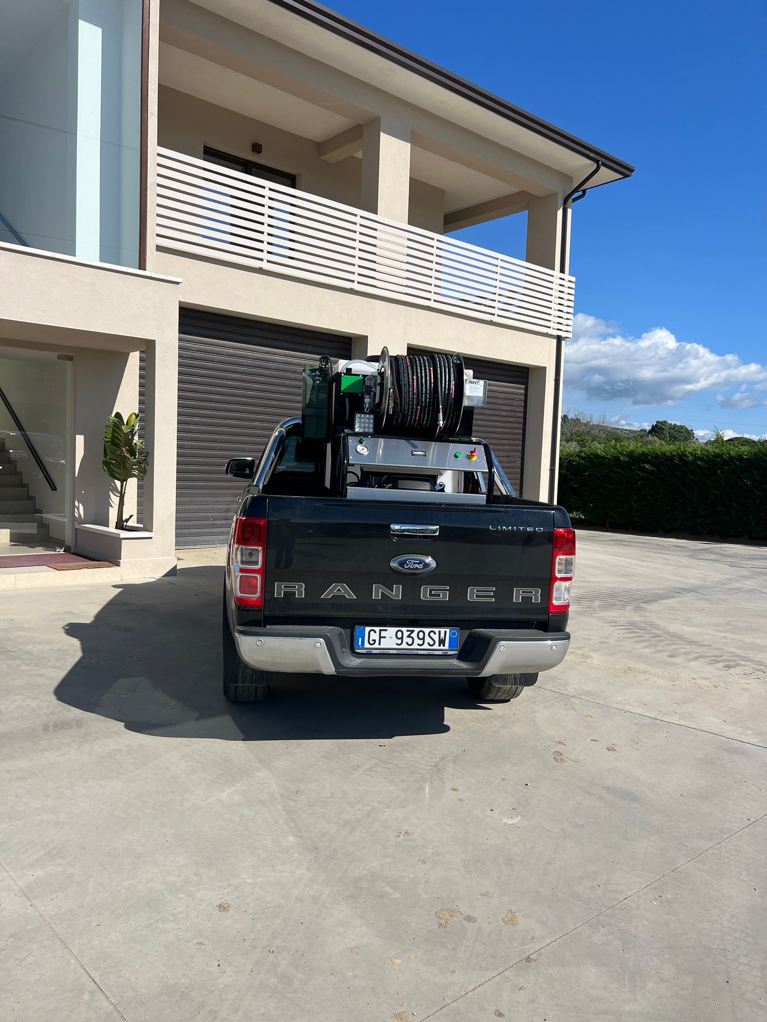 Un pick-up nero parcheggiato davanti a un edificio beige con un balcone in una giornata di sole.