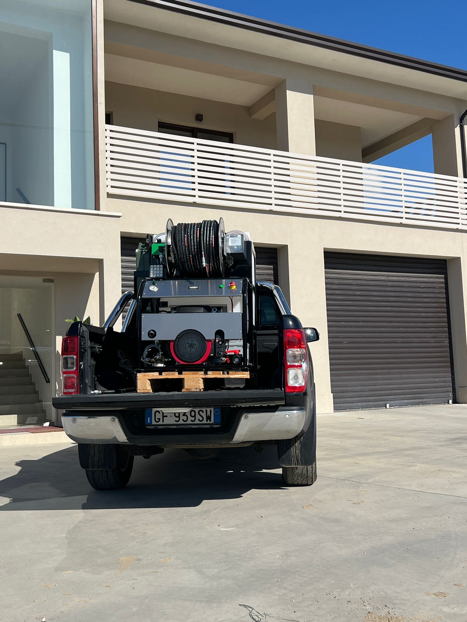 SUV nero parcheggiato davanti a una casa moderna con balcone e porta del garage chiusa.