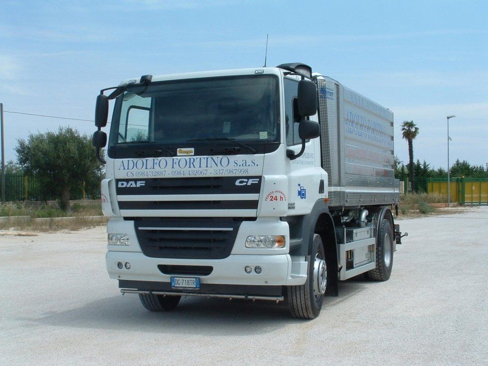 Un camion bianco da carico su una strada in una soleggiata zona industriale all'aperto.