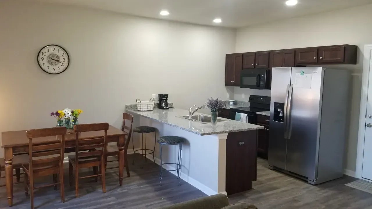 Modern kitchen and dining area with wooden table, island counter, and stainless steel appliances