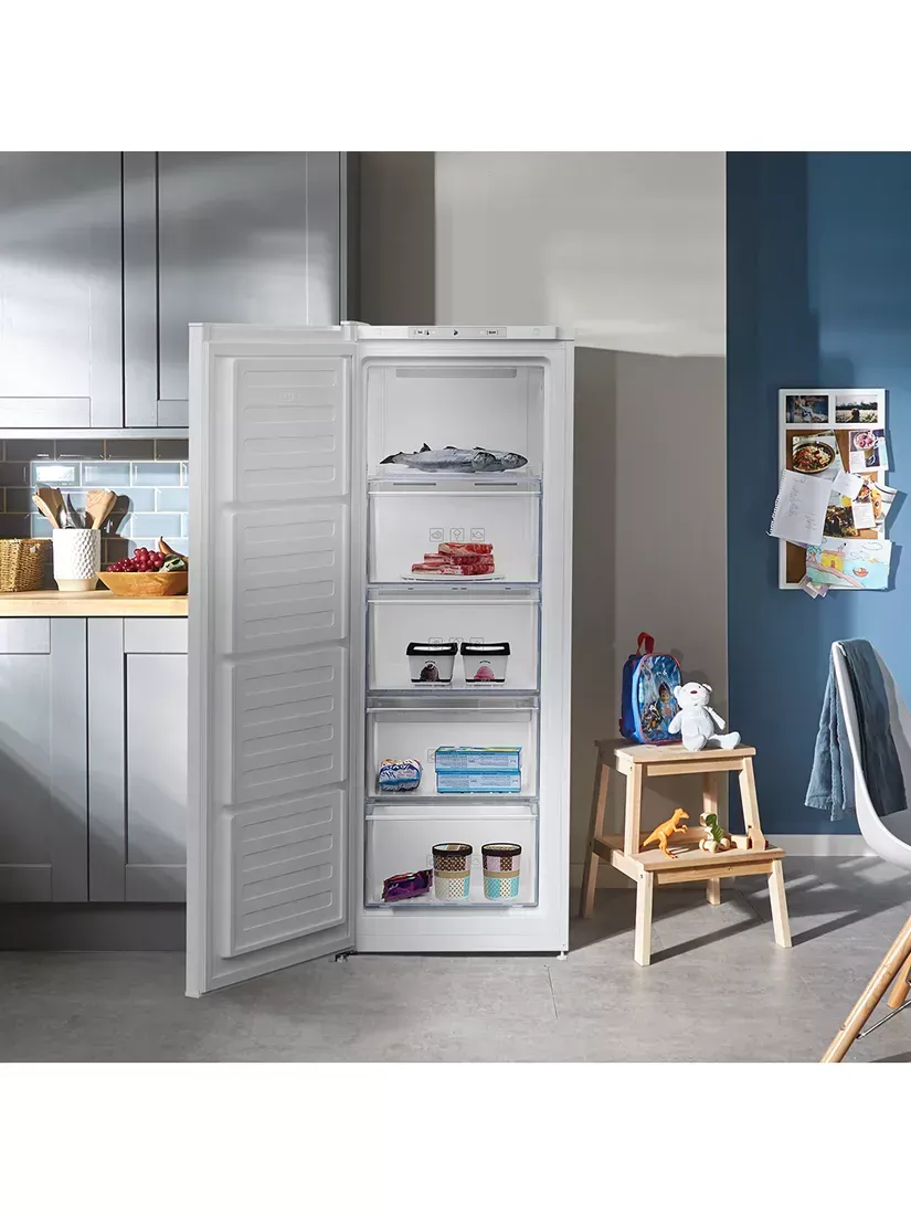 A white freezer is sitting in a kitchen with the door open.