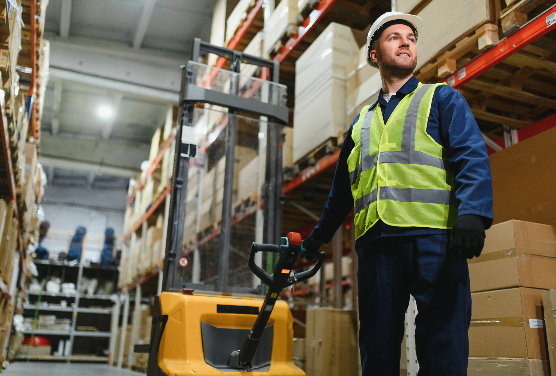 Warehouse aisle with stacked cardboard boxes on tall orange shelves.