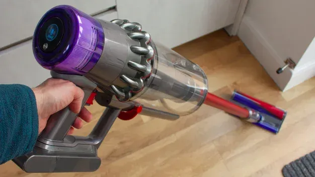 A person is holding a vacuum cleaner on a wooden floor.