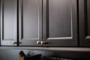 Dark kitchen cabinets with silver knobs and a blurred countertop below