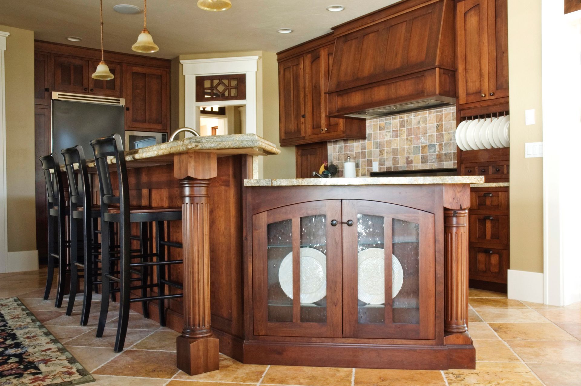 Wooden kitchen with island, tall bar stools, stainless fridge, and warm cabinetry
