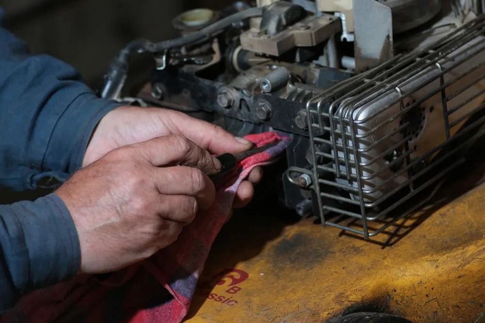 A Man is Working on a Lawn Mower in a Garage — Diamond Service Centre In Lismore, NSW
