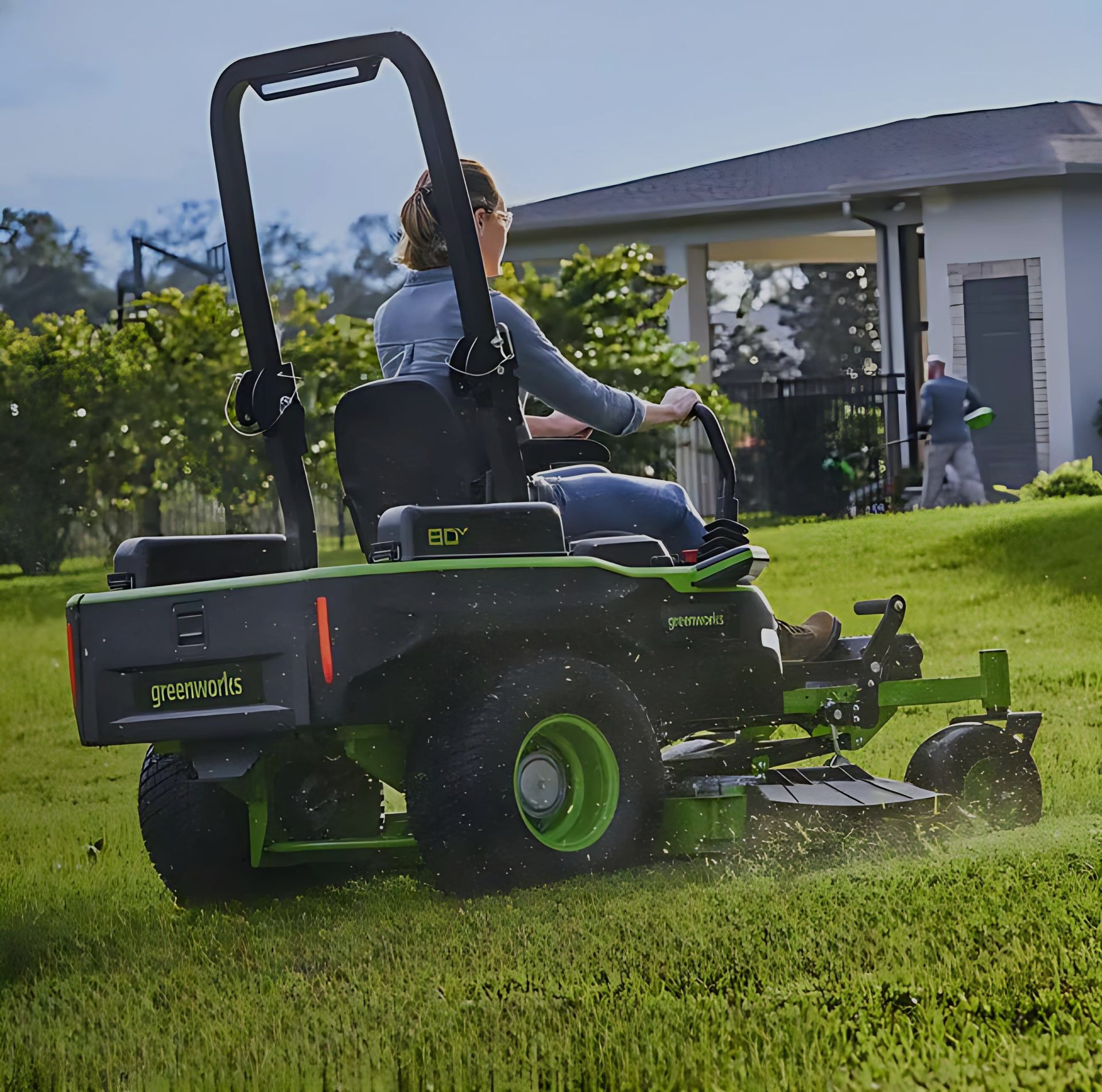 Woman On Green Riding Lawnmower, Cutting Grass In A Yard, Sunny Day — Diamond Service Centre In Lismore, NSW