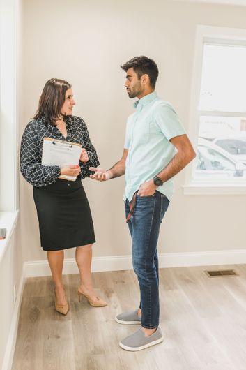 Two coworkers high-five across a desk in a bright office with a laptop and papers.