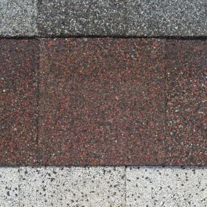 Three horizontal bands of textured roofing shingles in gray, reddish-brown, and light gray