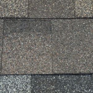 Close-up of gray asphalt shingles with a textured, mottled surface