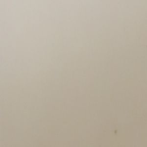 Plain beige wall with a small dark spot near the lower right corner