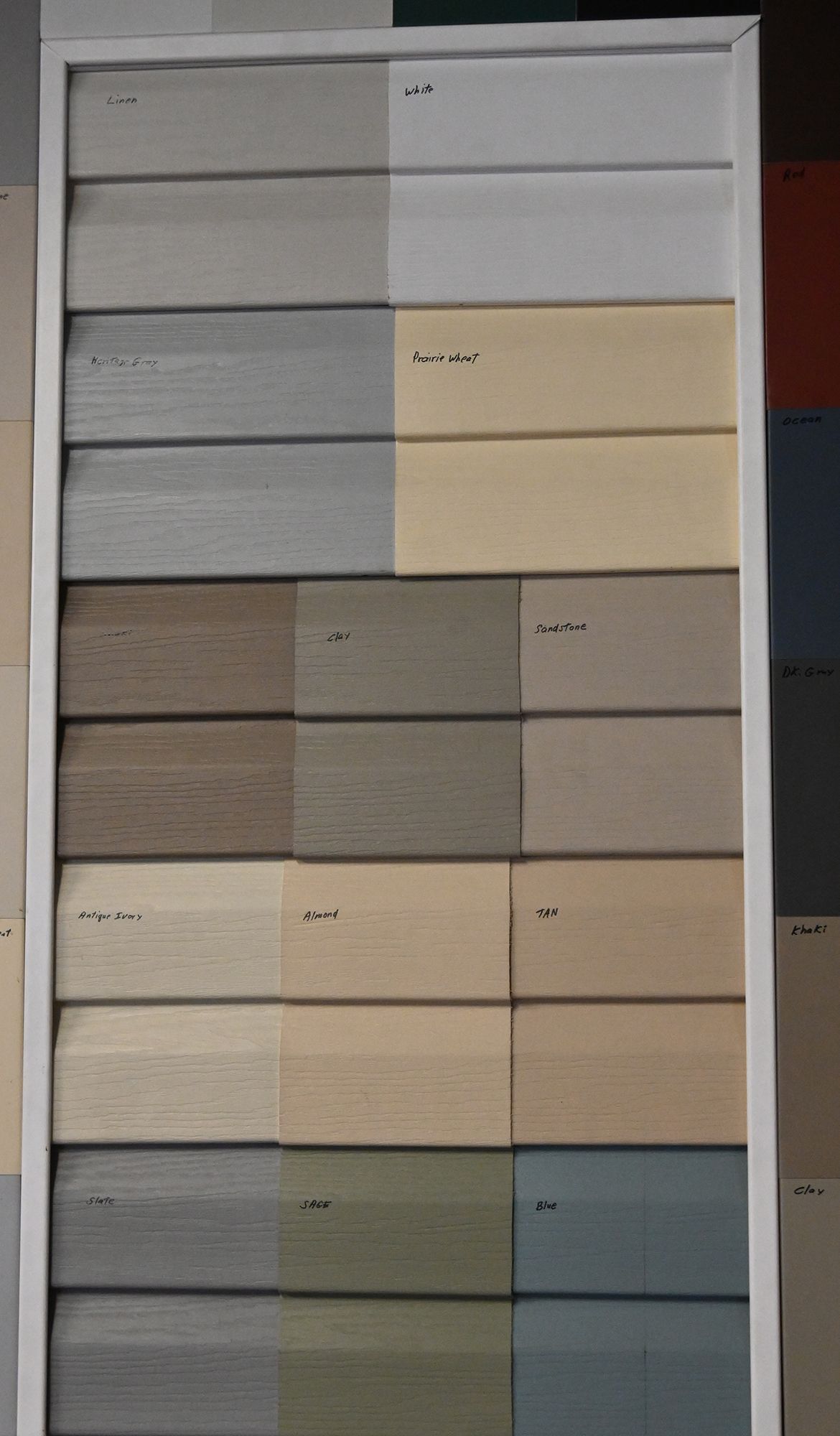 Stacked paint color sample cards in neutral beige, gray, and blue tones on a display board