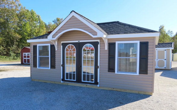 Small tan modular office building with double glass doors and white-trimmed windows on a gravel lot