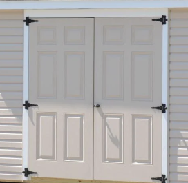 White double exterior doors with black hinges on a beige siding wall