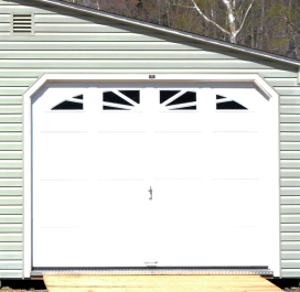 White garage door on a light green house exterior with decorative windows above.