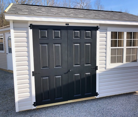 Black double garage doors on a white house exterior with a small window beside them