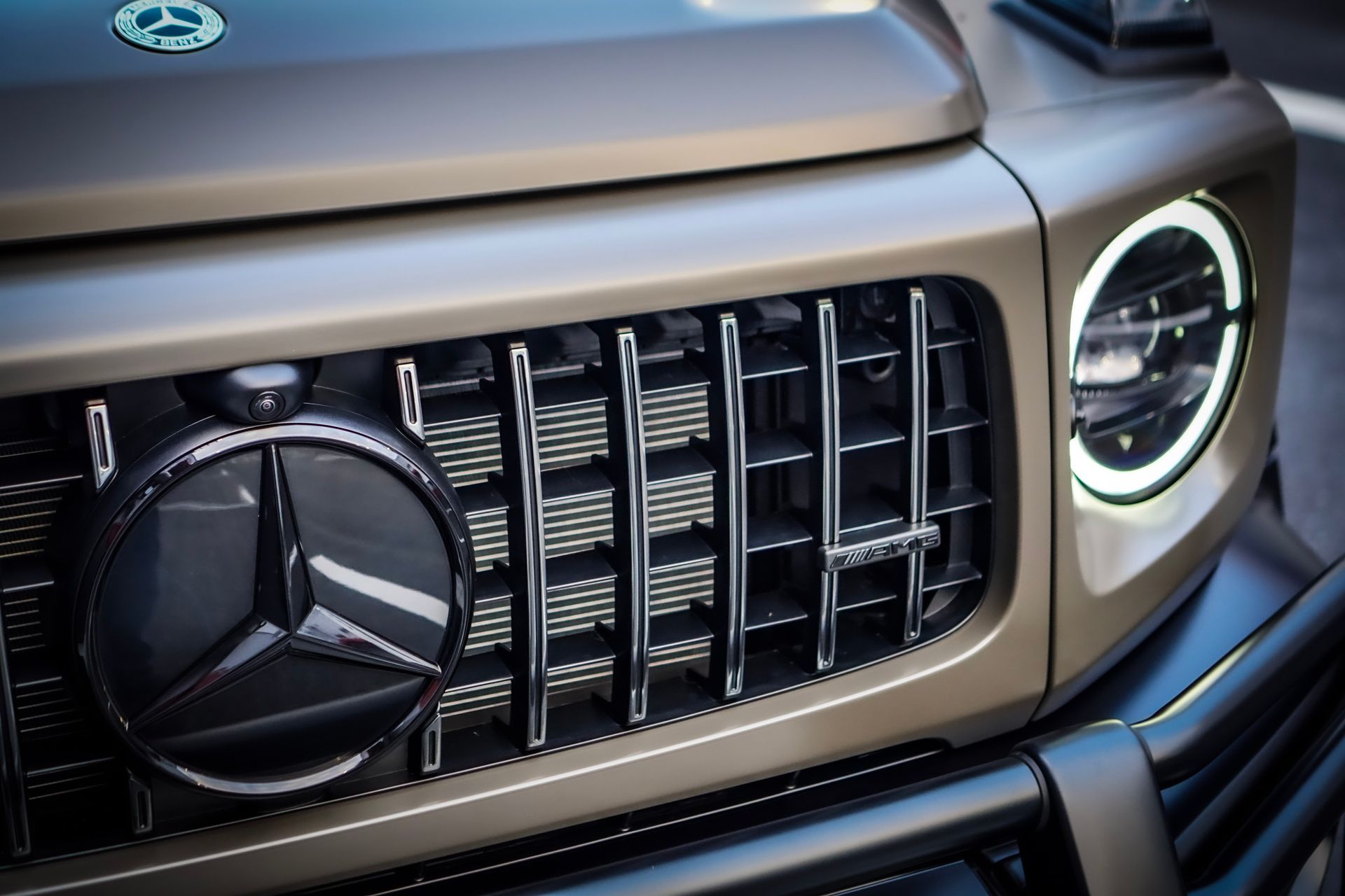 Close-up of a brown Mercedes-Benz G-Class front grille, showing the emblem and headlights.