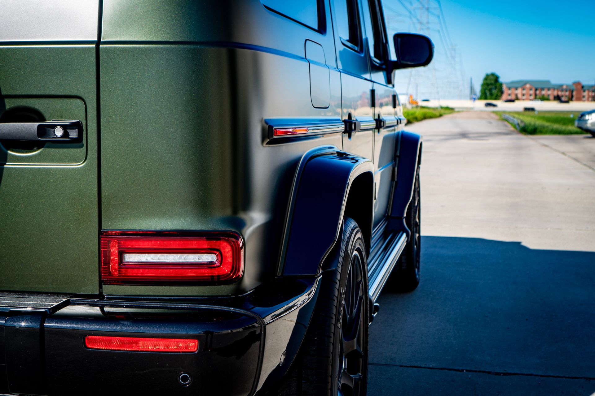 Green and black Mercedes-Benz G-Class SUV, rear quarter view, parked on pavement.