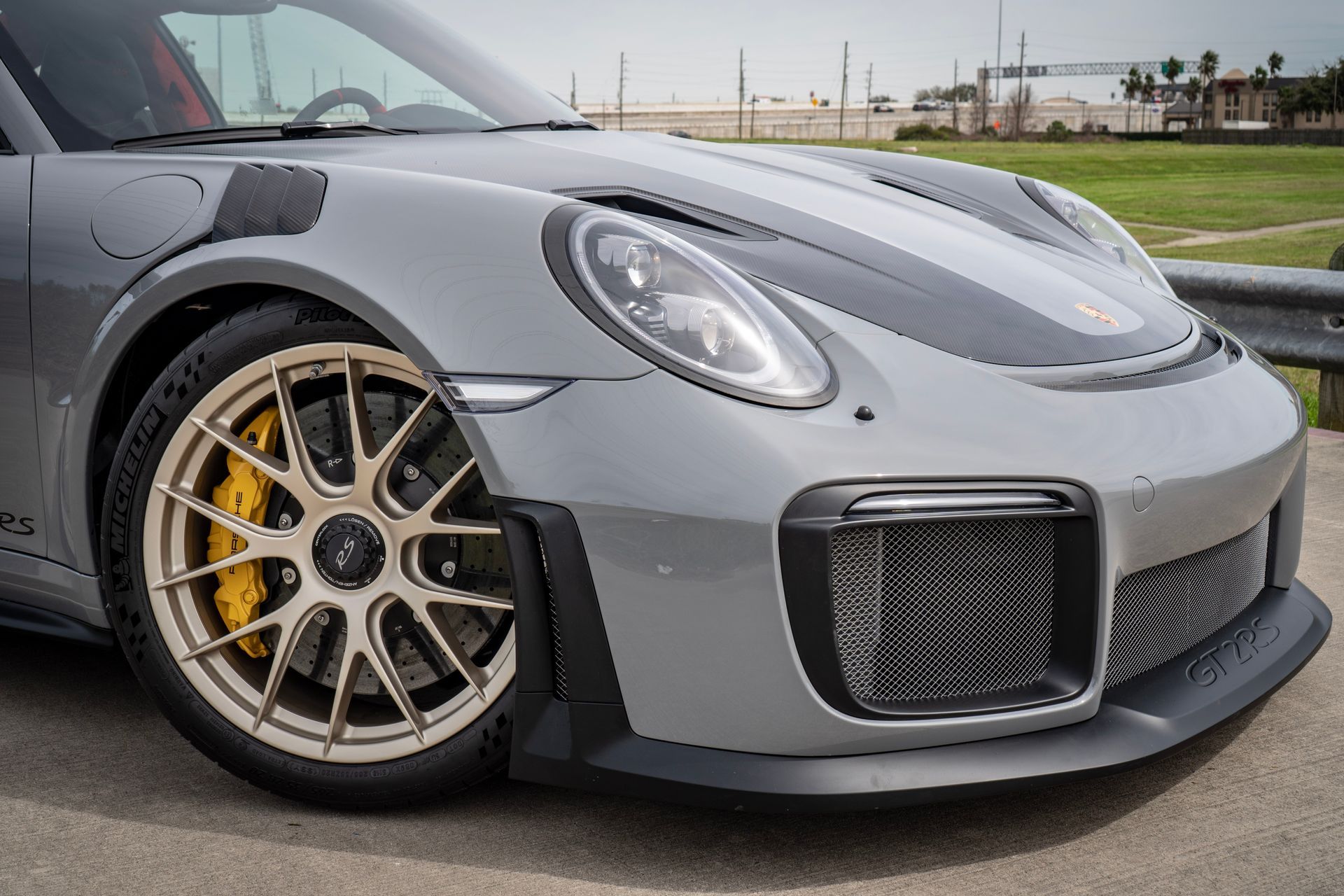 Gray Porsche 911 GT2 RS sports car with gold wheels, and yellow brake calipers.